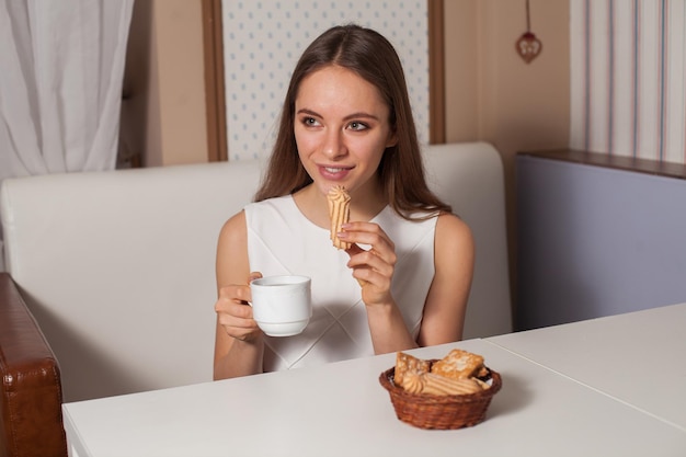 Mulher comendo biscoitos e bebendo chá quente no café