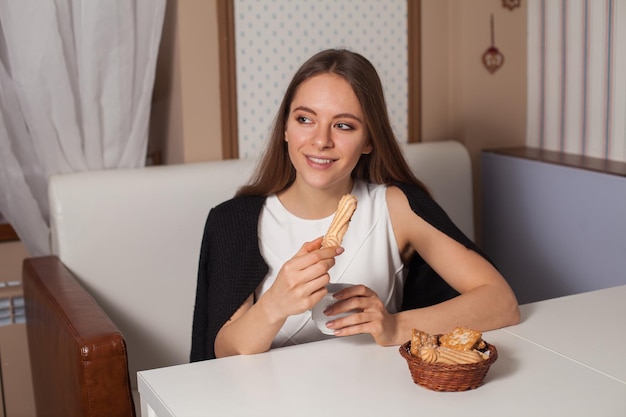 Mulher comendo biscoitos e bebendo chá quente no café