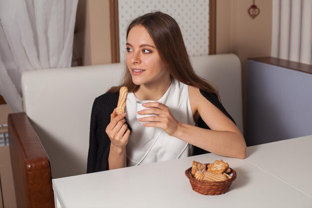 Mulher comendo biscoitos e bebendo chá quente no café