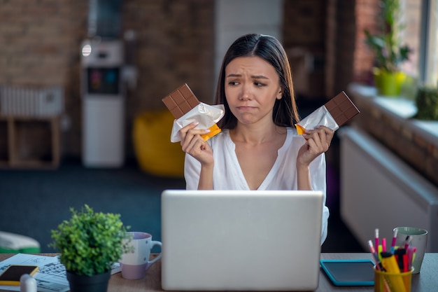 Mulher comendo chocolate no trabalho