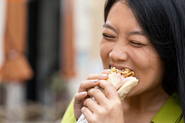 Mulher comendo comida de rua ao ar livre