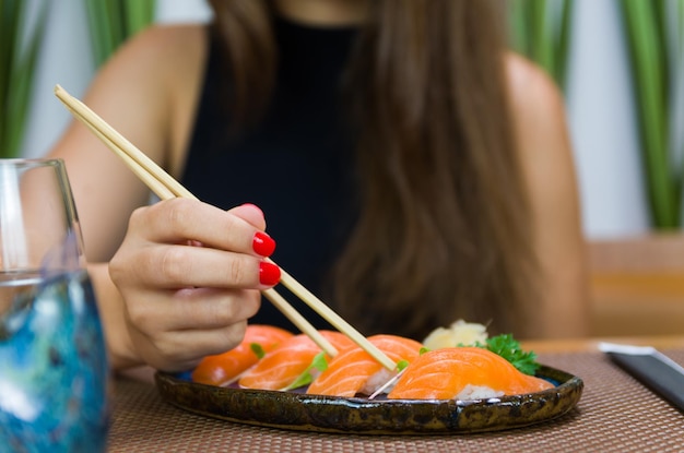 Mulher comendo delicioso sushi closeup em pauzinhos