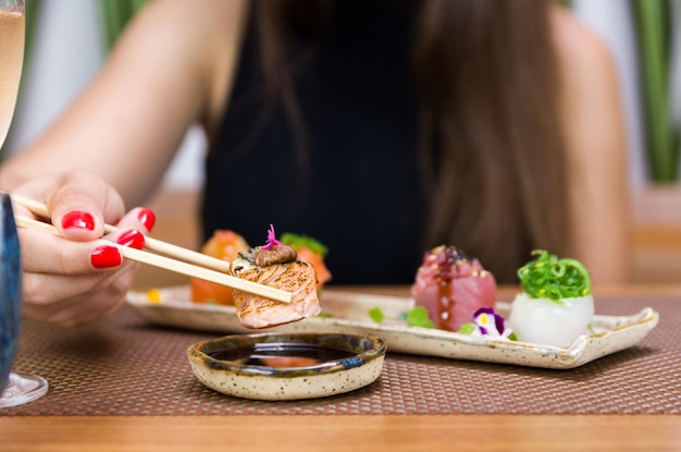 Mulher comendo delicioso sushi gunkan closeup em pauzinhos