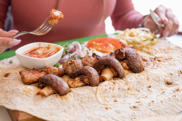 Mulher comendo kebab grelhado com pão pita e legumes na bandeja no café de rua de fast-food de verão