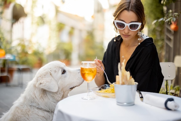 Mulher comendo macarrão com seu cachorro branco fofo no restaurante