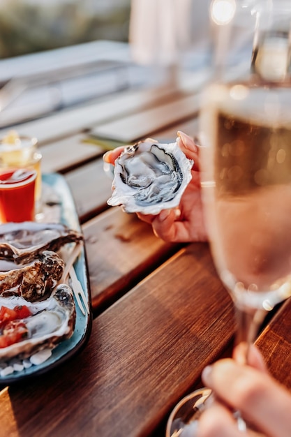 Mulher comendo ostras frescas e bebendo vinho prosecco gelado no pôr do sol de verão delícias de frutos do mar