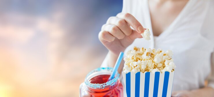 Foto mulher comendo pipoca com bebida em frasco de vidro