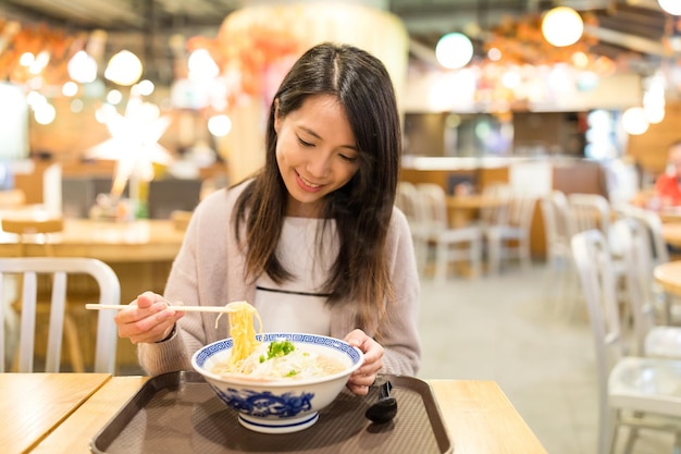 Mulher comendo ramen no restaurante