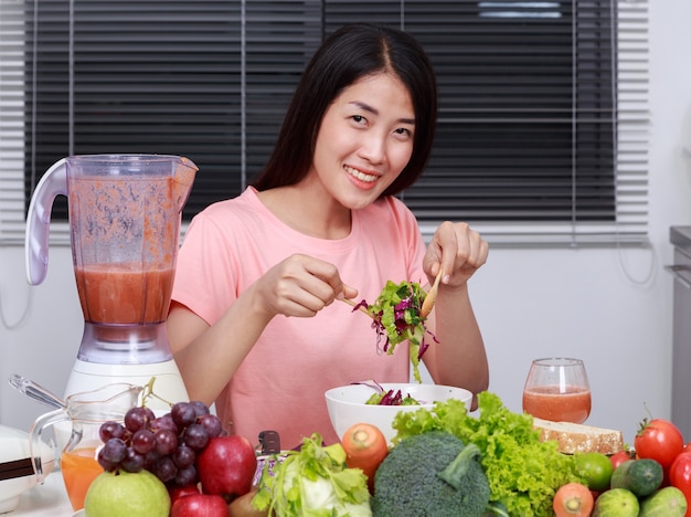 mulher comendo salada na cozinha