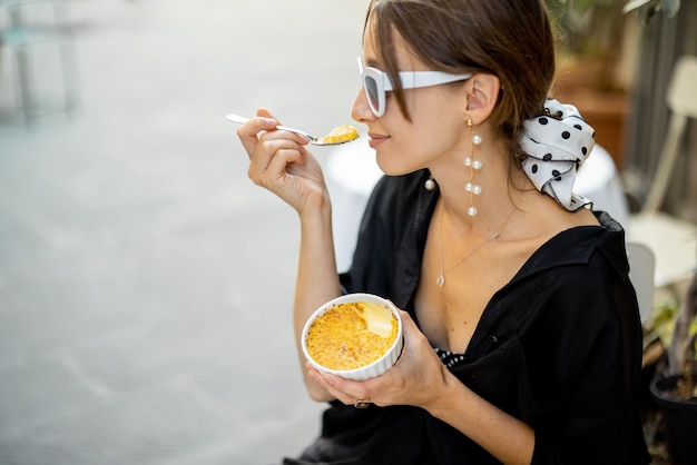 Mulher comendo sobremesa com creme brulee no restaurante ao ar livre