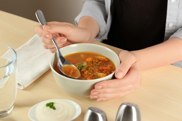 Mulher comendo sopa de lentilha saborosa na mesa