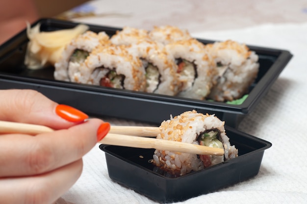 Mulher comendo sushi entregue em casa.