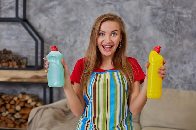 Mulher compara dois frascos de detergente em casa limpando a sala de estar. Trabalho de casa. Lugar para texto na garrafa