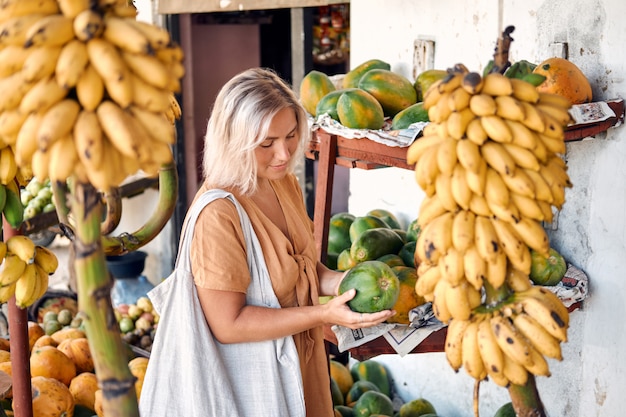 Mulher compra mamão fresco no mercado local Tropical