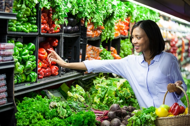 Mulher comprando legumes na seção orgânica