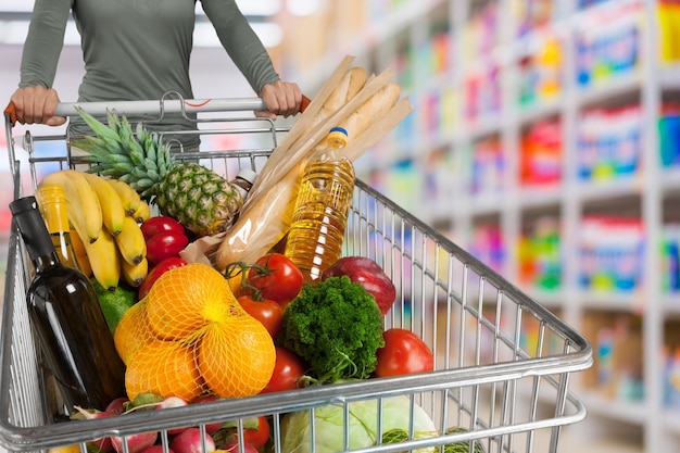 Mulher comprando no supermercado com um carrinho de compras