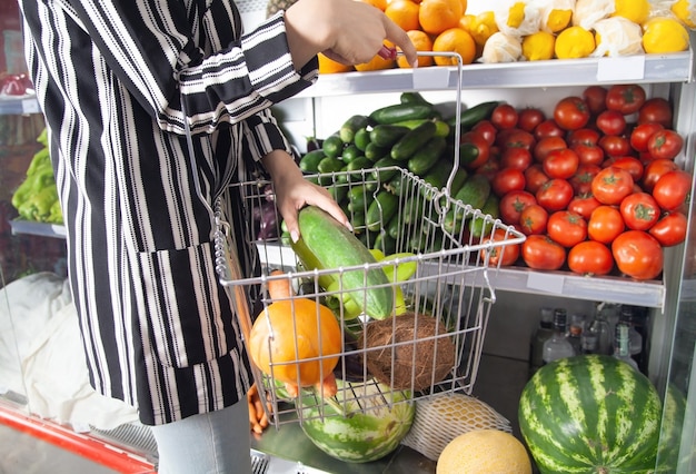 Mulher comprando pepino na loja de alimentos.