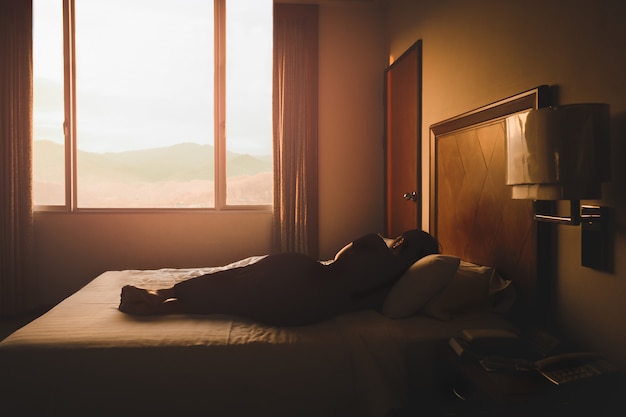 Mulher conceitual, dormindo em uma cama com uma bela vista ao pôr do sol.