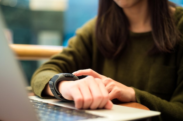 Foto mulher conectando relógio inteligente com computador portátil