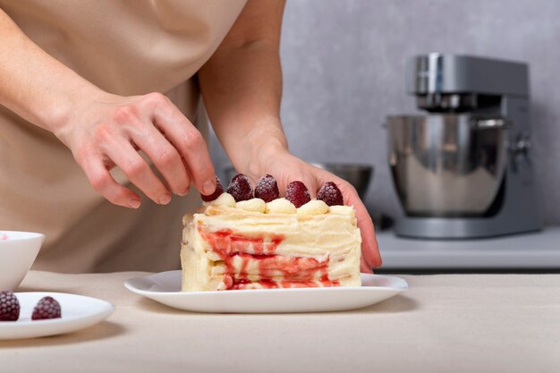 Mulher confeiteira decora bolo com frutas. Bolo de creme de baunilha com recheio de frutos silvestres.