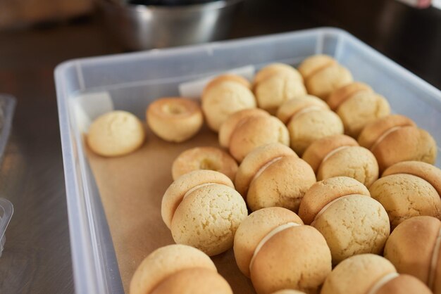 Mulher confeiteira enche muffin fresco com caramelo de saco de confeitar plástico fazendo deliciosa sobremesa natural na cozinha em casa vista de cima