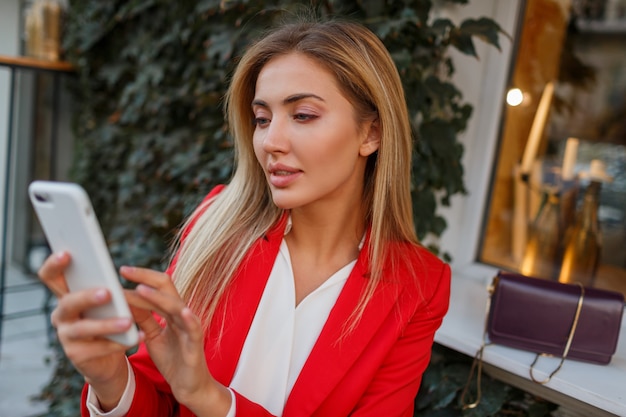 Mulher confiante com smartphone passando um tempo no café da cidade