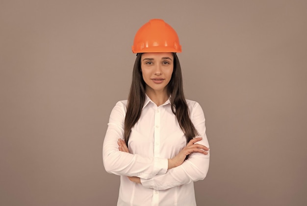 Mulher confiante em capacete protetor e camisa branca cruzou negócios de mãos