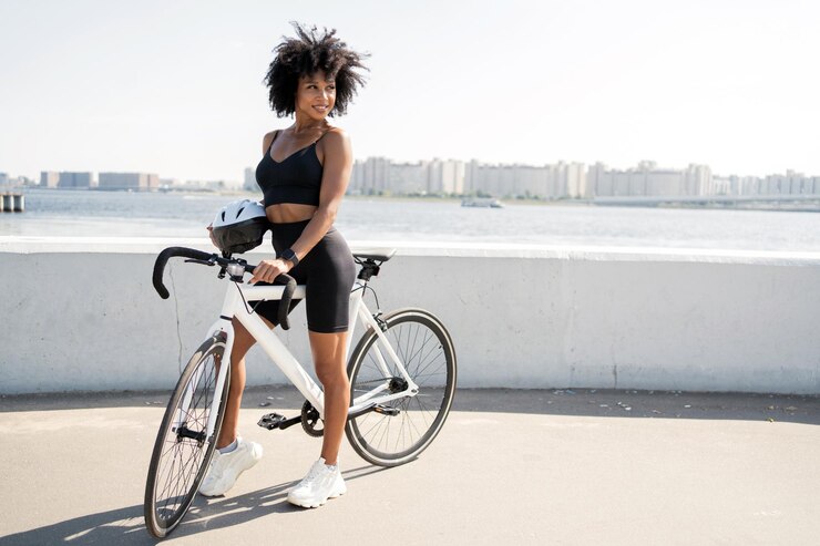 Foto mulher confiante feliz andando de bicicleta no transporte ecológico de roupas esportivas