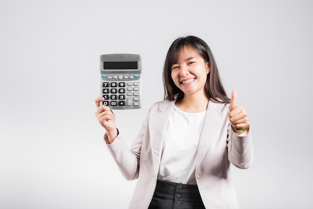 Mulher confiante sorrindo segurando calculadora eletrônica e mostrando o polegar para um bom gesto