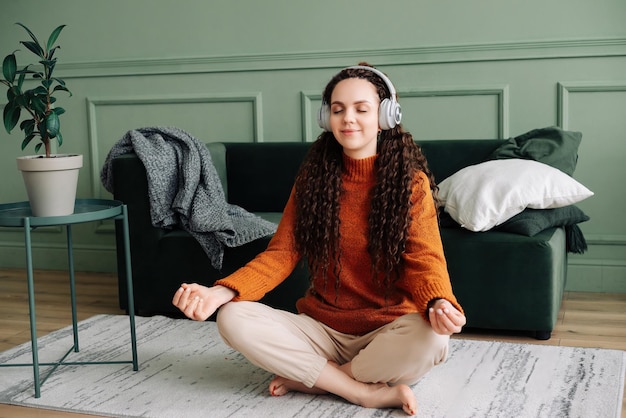 Mulher consciente encontrando paz interior por meio de ioga e meditação com música e podcasts relaxantes Relaxando em casa com ioga e meditação jovem encontrando equilíbrio mental