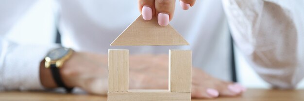 Mulher construir casa de cubos de madeira na mesa.