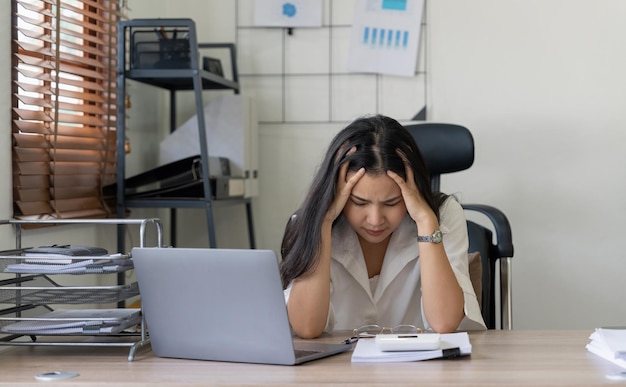 Mulher contabilista cansada sente dor de cabeça estressada mulher trabalhadora na mesa de negócios em um escritório de negócios