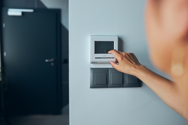 Mulher controlando o escritório com painel de tela de toque digital instalado na parede no escritório em casa inteligente