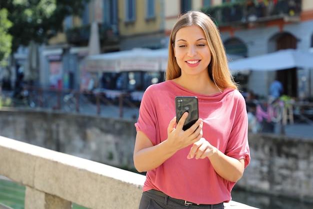 Mulher conversando com celular nos canais de navigli em milão, itália