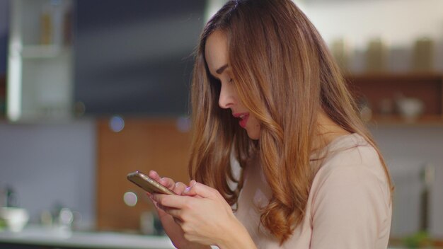 Mulher conversando no smartphone em casa Menina usando celular na cozinha