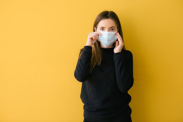 Mulher coronavírus em fundo amarelo em proteção facial de máscara cirúrgica