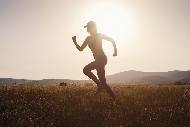 Mulher correndo no campo de verão ao pôr do sol
