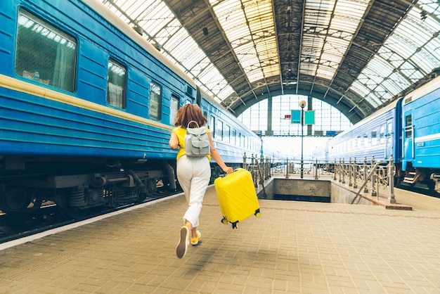 Mulher correndo pela estação ferroviária com malas atrasadas para o trem