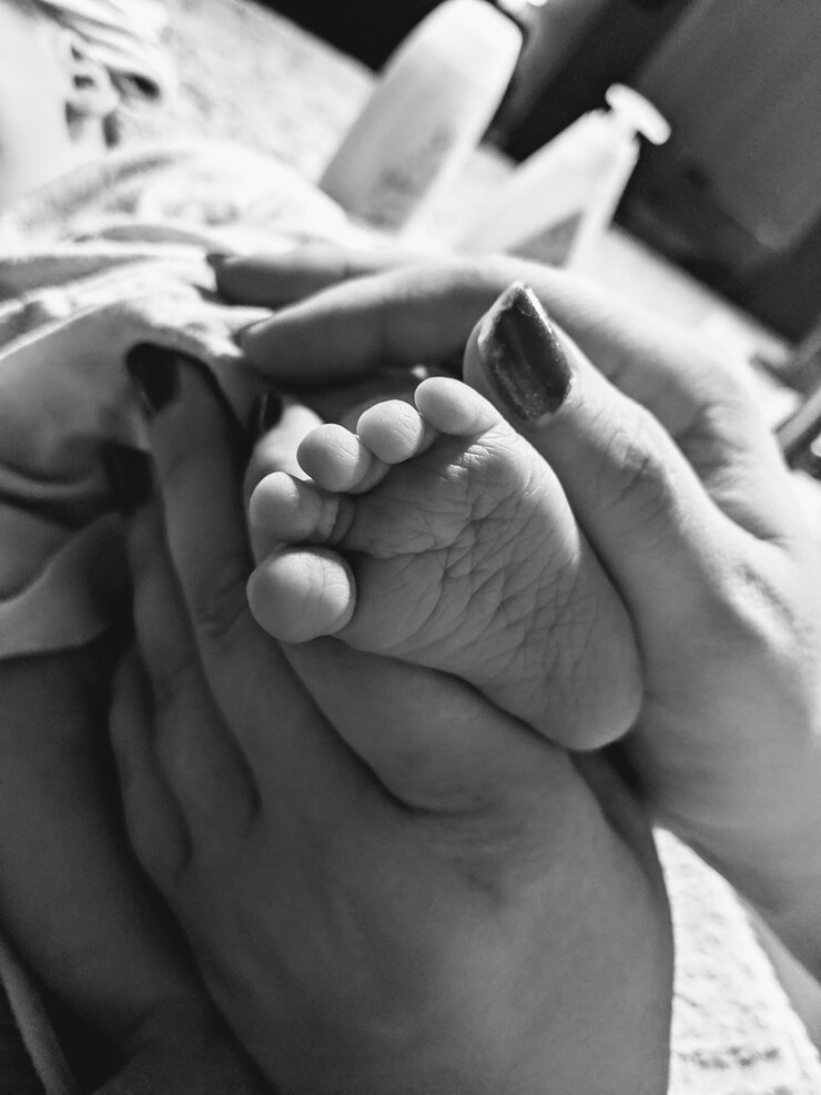 Foto mulher cortada segurando a perna do bebê em casa