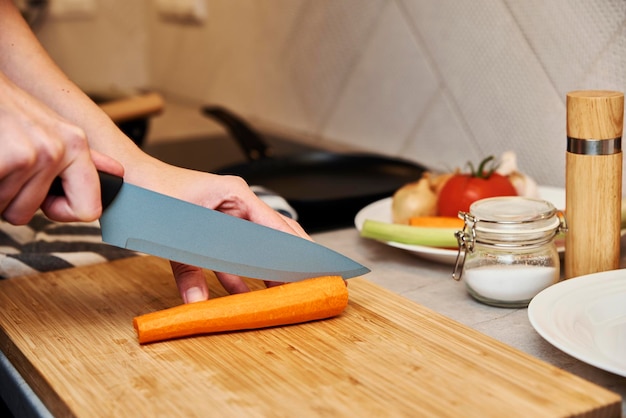 Mulher cortando cenoura na cozinha de perto