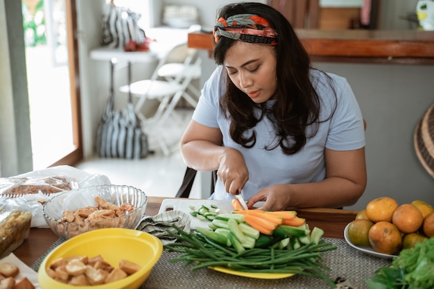 Foto mulher cortando cenouras para o jantar