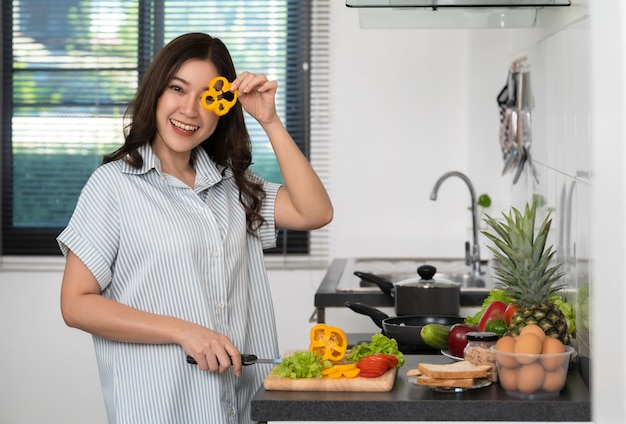 Mulher cortando legumes para preparar alimentos saudáveis na cozinha em casa