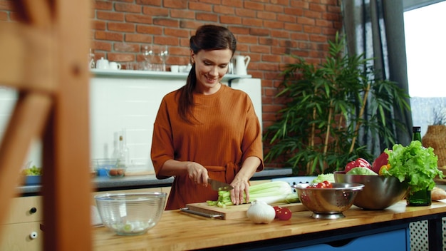Foto mulher cortando legumes para salada na cozinha dona de casa cozinhando refeição saudável