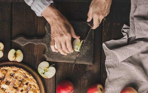 Mulher cortando maçãs para torta na mesa de madeira marrom