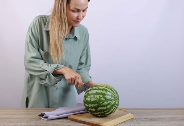 mulher cortando melancia com uma faca em uma placa