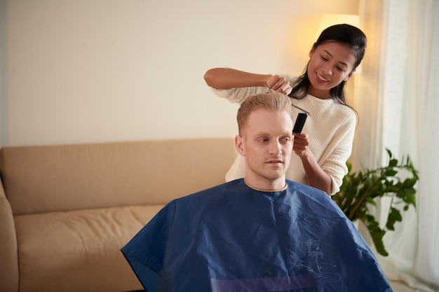 Mulher cortando o cabelo do namorado