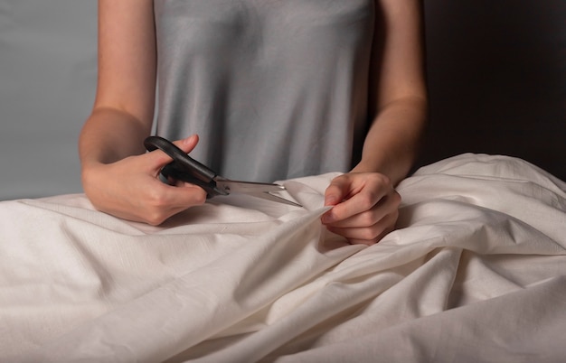 Mulher cortando tecido de algodão bege com tesoura de costura mãos de costureira closeup