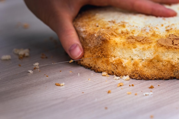 Foto mulher cortando torta de queijo de esponja com coco em uma mesa de madeira