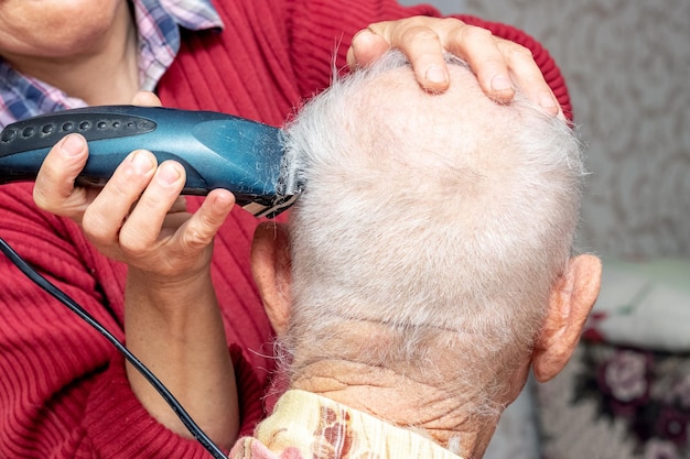 Mulher corte de cabelo um homem idoso com um aparador Corte de cabelo em casa