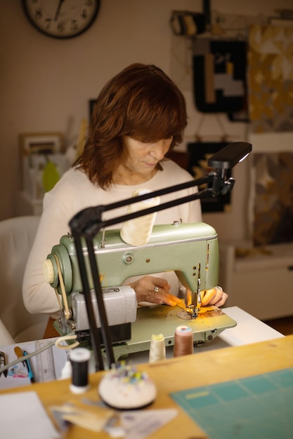 Mulher costurando tecido com uma máquina de costura vintage retro criação de moda e alfaiataria